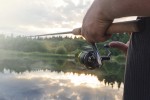 The man catches a fishing-rod fish on a reservoir.